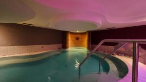 a swimming pool in a hotel with a purple ceiling at Hotel Angelo in Comano Terme
