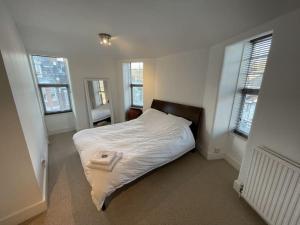 a bedroom with a bed with white sheets and windows at Spacious two bedroom flat in prestigious Highgate. in London
