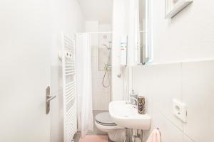 a white bathroom with a toilet and a sink at TM Studio in Dortmund
