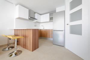 kuchnia z białymi szafkami i żółtym stołkiem w obiekcie Levante Sunset Luxury apartment Don Miguel w mieście Benidorm
