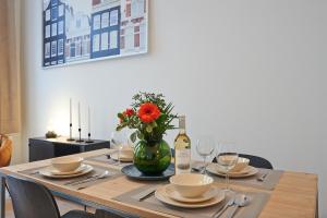einen Tisch mit einer Vase Blumen und einer Flasche Wein in der Unterkunft South Cosy Residence in Brüssel