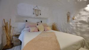 a bedroom with a white bed with pink and yellow pillows at Cueva OTTO Privada in Baza