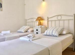 two beds in a bedroom with a lamp on a night stand at Mykonos Dot - The Villas in Mikonos