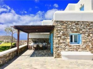 - un bâtiment avec un mur en pierre et une terrasse dans l'établissement Mykonos Dot - The Villas, à Mykonos