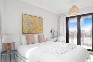 Un dormitorio blanco con una gran cama blanca y una ventana en 3bed Penthouse 10min to Wimbledon tennis courts, en Londres