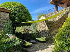 a patio with a stone wall and a yellow umbrella at GITE LES GRANDES VIGNES, SUD Ardèche, indépendant et privatisé, piscine chauffée, climatisation, SPA, 11 chambres, 8 salles de bains in Sanilhac
