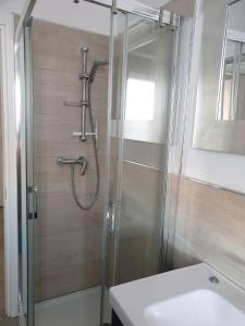 a shower with a glass door next to a sink at Condominio Schiusa in Grado