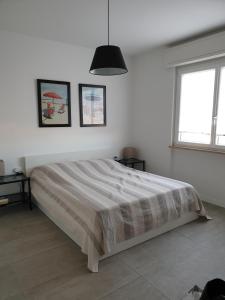 a white bedroom with a bed and two windows at Condominio Schiusa in Grado