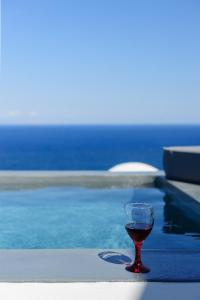 a glass of wine sitting next to a swimming pool at LF Suites & Villas in Imerovigli