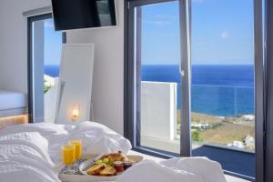 a plate of food on a bed with a view of the ocean at LF Suites & Villas in Imerovigli +50 photos