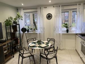 a table and chairs in a kitchen with a clock on the wall at Apartament Błogi Sen III - komfortowy nocleg w spokojnej lokalizacji in Zabrze