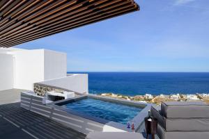 a swimming pool on the side of a house with the ocean at LF Suites & Villas in Imerovigli