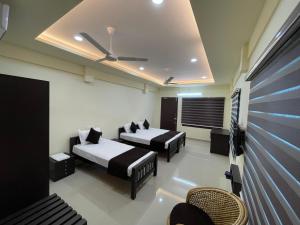 um quarto de hotel com duas camas e uma televisão em UPPERCREST RESIDENCY PALA em Pala