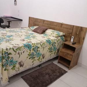 a bedroom with a bed with a wooden headboard and a table at Aeroporto House in Macapá