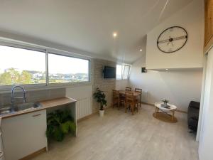 cocina y sala de estar con un reloj grande en la pared en Bel appartement à deux minutes de la plage, en Courseulles-sur-Mer