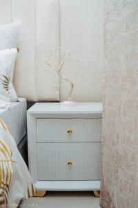 a white nightstand with a vase on it in a bedroom at Sunset Gold-2 Bedrooms Apartment in Fourways