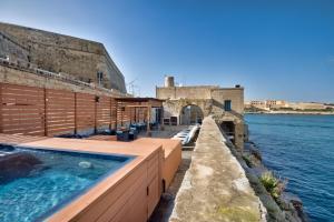 a building with a swimming pool next to the water at UNIQUE Waterfront Valletta House in Valletta
