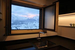 ventana de cocina con fregadero y vistas a las montañas en Ferienhaus Oberguet, en Unterwasser