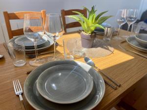 una mesa de madera con platos y copas de vino. en Bel appartement à deux minutes de la plage, en Courseulles-sur-Mer