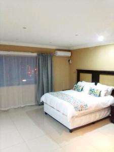 Un dormitorio con una cama grande y una ventana en Mkhandi Self Catering en Durban