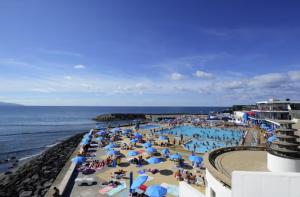 a beach with a bunch of people and the ocean at Mar Grande Apartment in Ribeira Grande