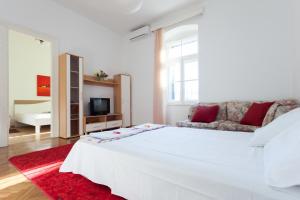 a white bedroom with a large white bed and a couch at Apartment Red Coral in Dubrovnik