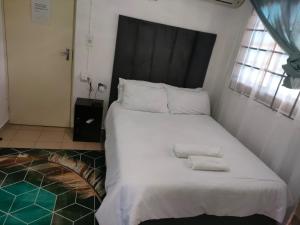 Erima Lodge في جوهانسبرغ: غرفة نوم بسرير كبير عليها منشفتين