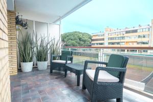 a balcony with chairs and tables and a building at Gavà Beach Apartment in Gavà