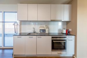 La cuisine est équipée de placards blancs et d'un four micro-ondes. dans l'établissement SKYLINE Exclusive Penthouse Apartments, à Bâle
