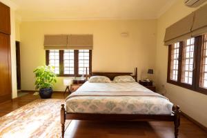 a bedroom with a bed in a room with windows at Luho 187 in Bangalore