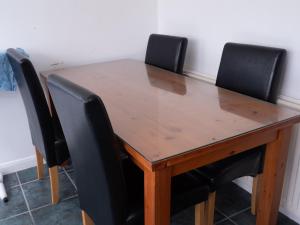 a wooden table with four black chairs around it at Convenient 3BR close to QE Hospital & University of Birmingham in Birmingham