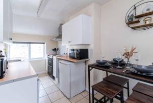 a kitchen with white cabinets and a table at Characterful 2 bedroom apartment - Central location in Castle Donington