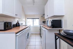 a white kitchen with white cabinets and a microwave at Characterful 2 bedroom apartment - Central location in Castle Donington