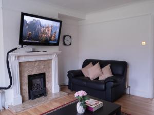 sala de estar con sofá y chimenea con TV en Convenient 3BR close to QE Hospital & University of Birmingham, en Birmingham
