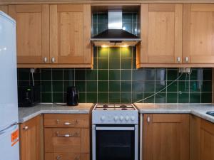 a kitchen with a stove and a green tiled wall at Convenient 3BR close to QE Hospital & University of Birmingham in Birmingham