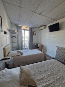 a hotel room with two beds and a television at Hôtel du Nord in Cannes