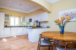 a kitchen with a wooden table with a vase of flowers at Villa Sea Renity - Palheiro Village by ALMA Holiday Rentals in Funchal