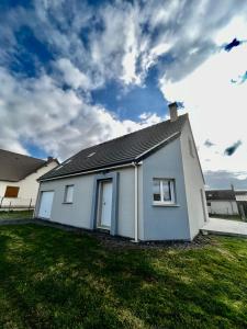 una casa blanca con un patio de hierba delante de ella en Maison 3 ch vue sur mer confortable lumineuse belle terrasse grand jardin 10 mn à pied de la plage - proche supérette et Omaha Beach en Vierville-sur-Mer