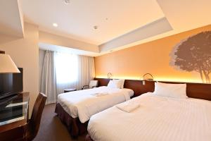 a hotel room with two beds and a flat screen tv at Hotel Keihan Sapporo in Sapporo
