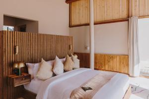 a bedroom with a large white bed with a wooden headboard at Caravan by Habitas Dakhla in Dakhla