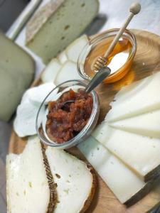 B&B CA' DEL PITUR CICOGNA في Cossogno: لوحة تقطيع مع الجبن وجارة الصلصة
