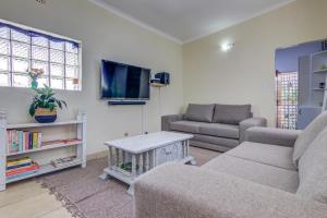a living room with a couch and a tv at Ovendales Self Catering Cottage in Benoni
