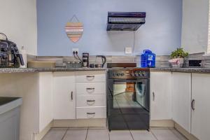 a kitchen with white cabinets and a black oven at Ovendales Self Catering Cottage in Benoni