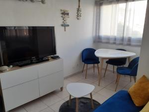 een woonkamer met een tv en een tafel en stoelen bij L'Escale Marine : Centre ville/ Plage in Bandol