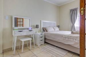 a bedroom with a bed and a desk with a mirror at Ovendales Self Catering Cottage in Benoni