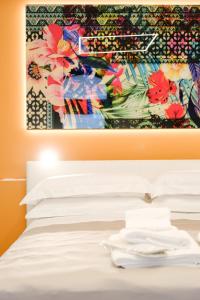 Ostuni Luxury Room في أوستوني: لوحة معلقة فوق سرير بمخدات بيضاء