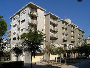 a tall white building with trees in front of it at Homely 1 bedroom flat with side sea view in Bibione