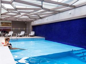 a woman is sitting in a swimming pool at Mercure Curitiba Batel in Curitiba