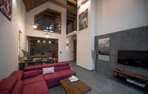 a living room with a red couch and a tv at Aspen Deluxe Residence & ASPEN cottage in Międzybrodzie Bialskie