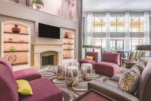 La Quinta Inn & Suites by Wyndham University Area Chapel Hill في دورهام: غرفة معيشة مع كراسي أرجوانية ومدفأة